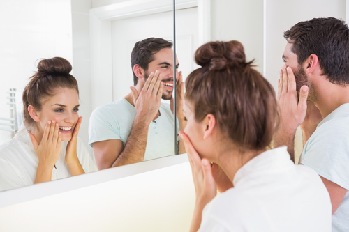 Young couple putting on face cream at home in the bathroom